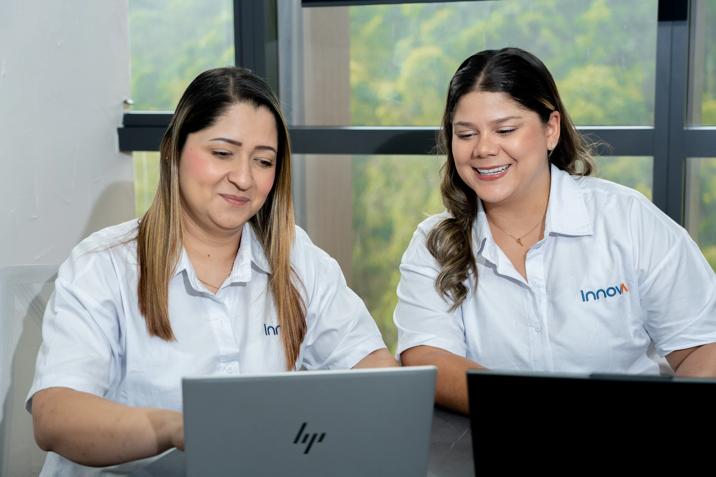 Dos asesoras de Innova colaborando frente a sus computadores