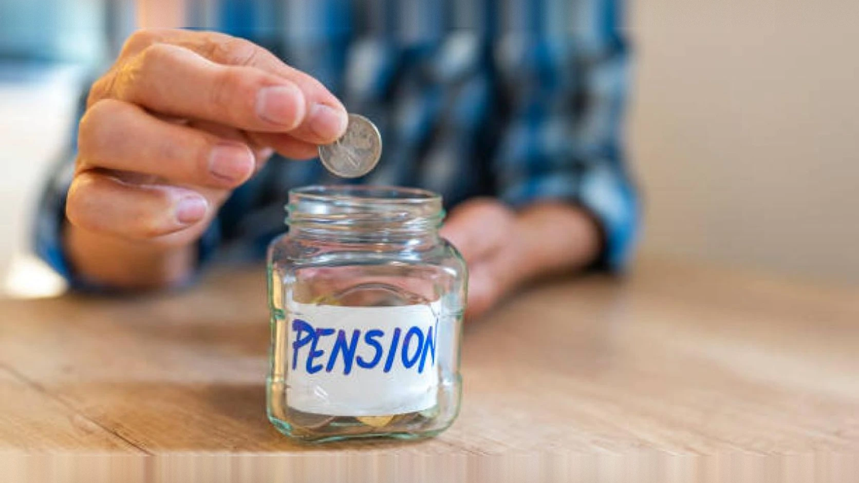 Mano depositando una moneda en un frasco rotulado como pensión